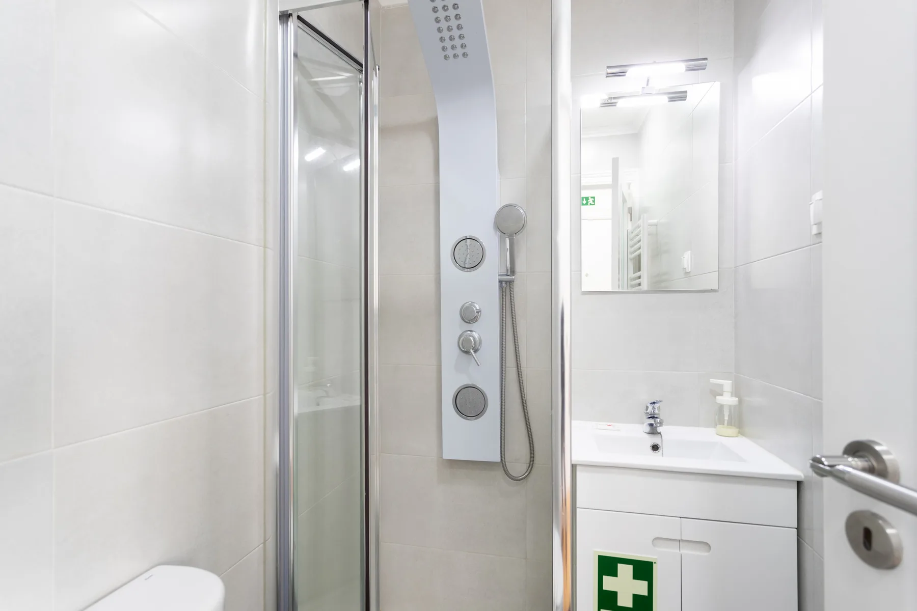 Un baño luminoso con ducha, lavabo y espejo en la pared.