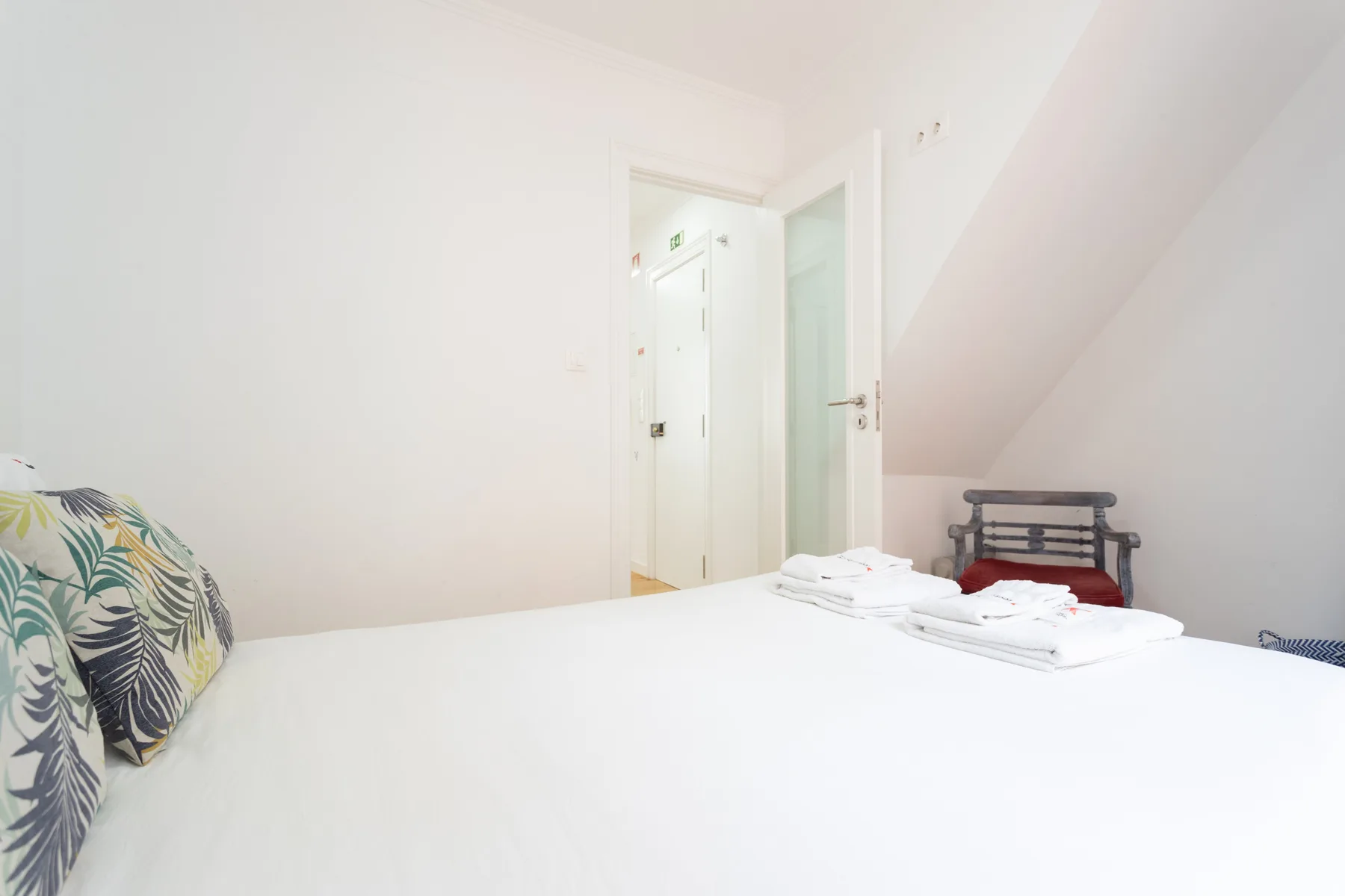 Un dormitorio con una cama bien hecha y una puerta abierta.