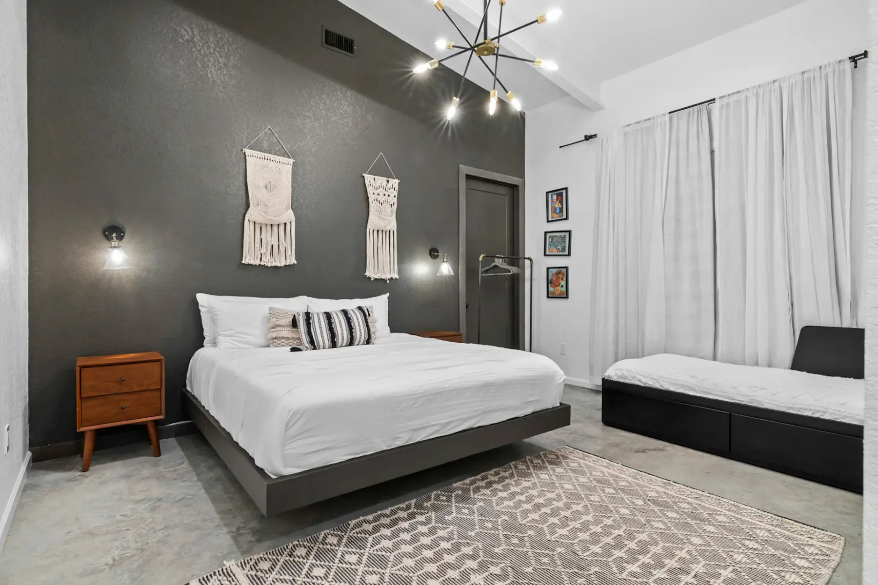 Modern bedroom with a white bed, dark accent wall, and patterned rug.