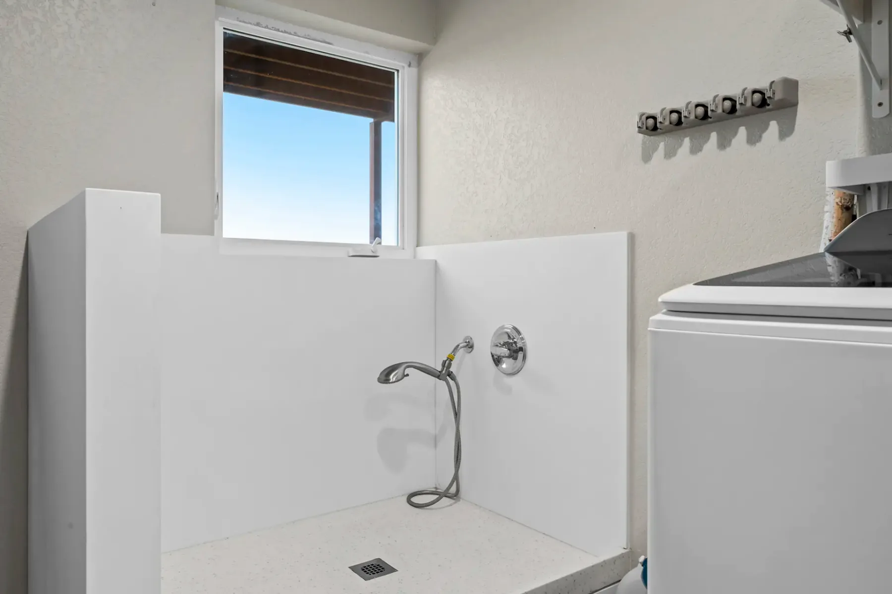 A shower area with a wall-mounted showerhead and a window.