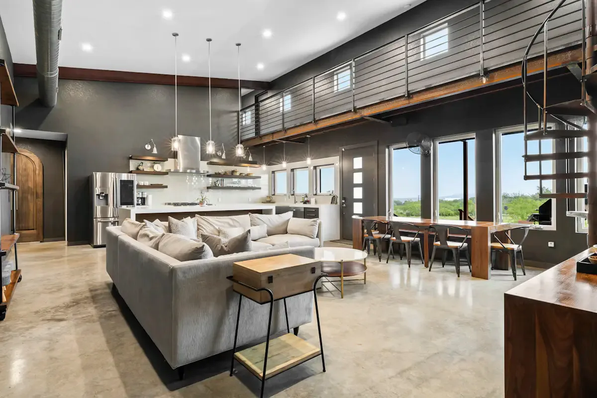 A spacious open-plan living area features seating, a kitchen, and a dining table.