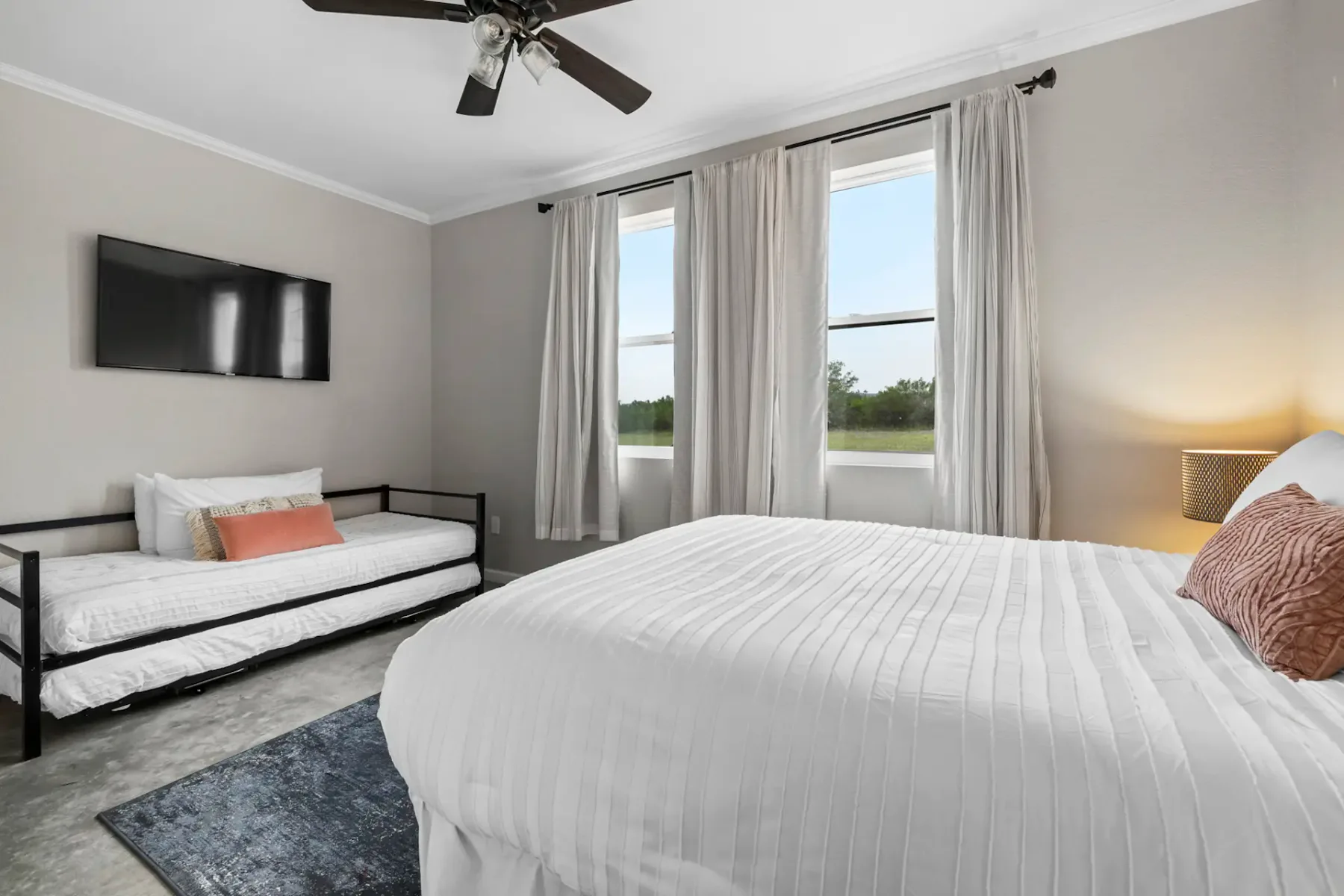 Bedroom with a large bed, a separate narrow bed, and curtained windows.