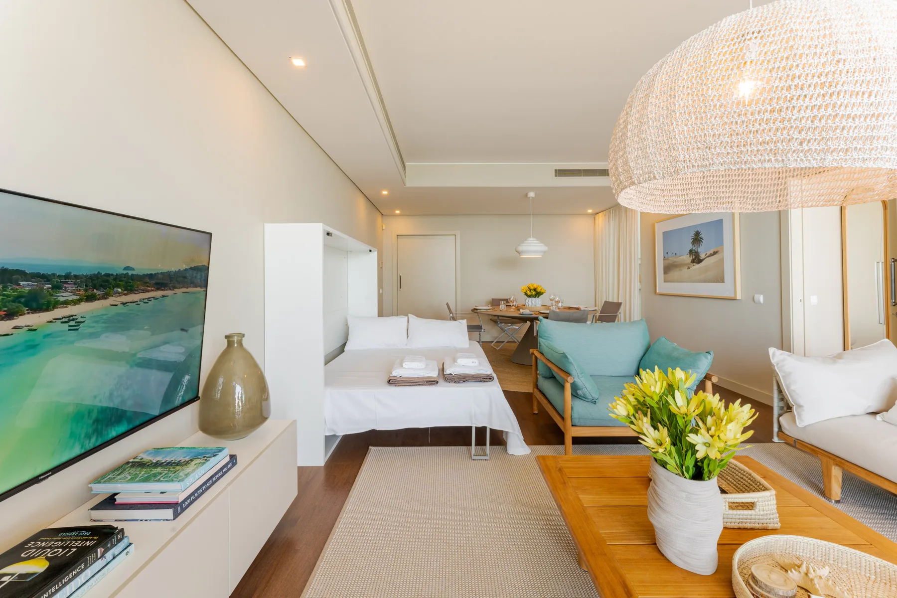 A bright living and sleeping area features a bed, seating, and a dining table.