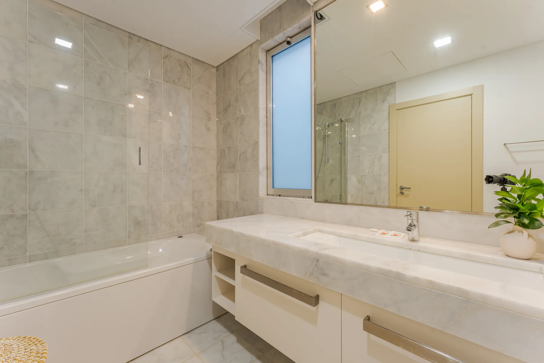A bathroom with a bathtub, a long vanity, and a large mirror.