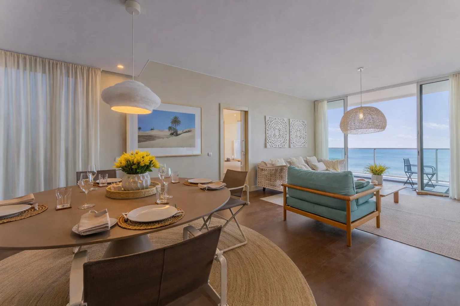 An open-plan dining and living area has large windows overlooking the ocean.