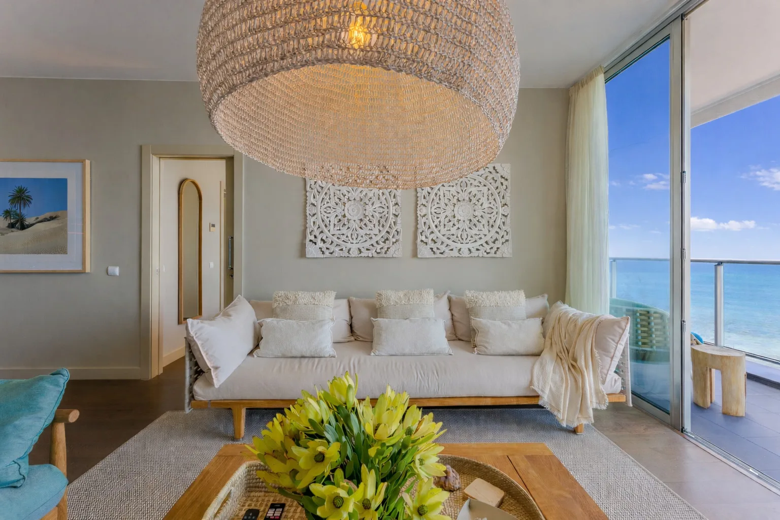 A bright living room with seating and large windows overlooking the ocean.