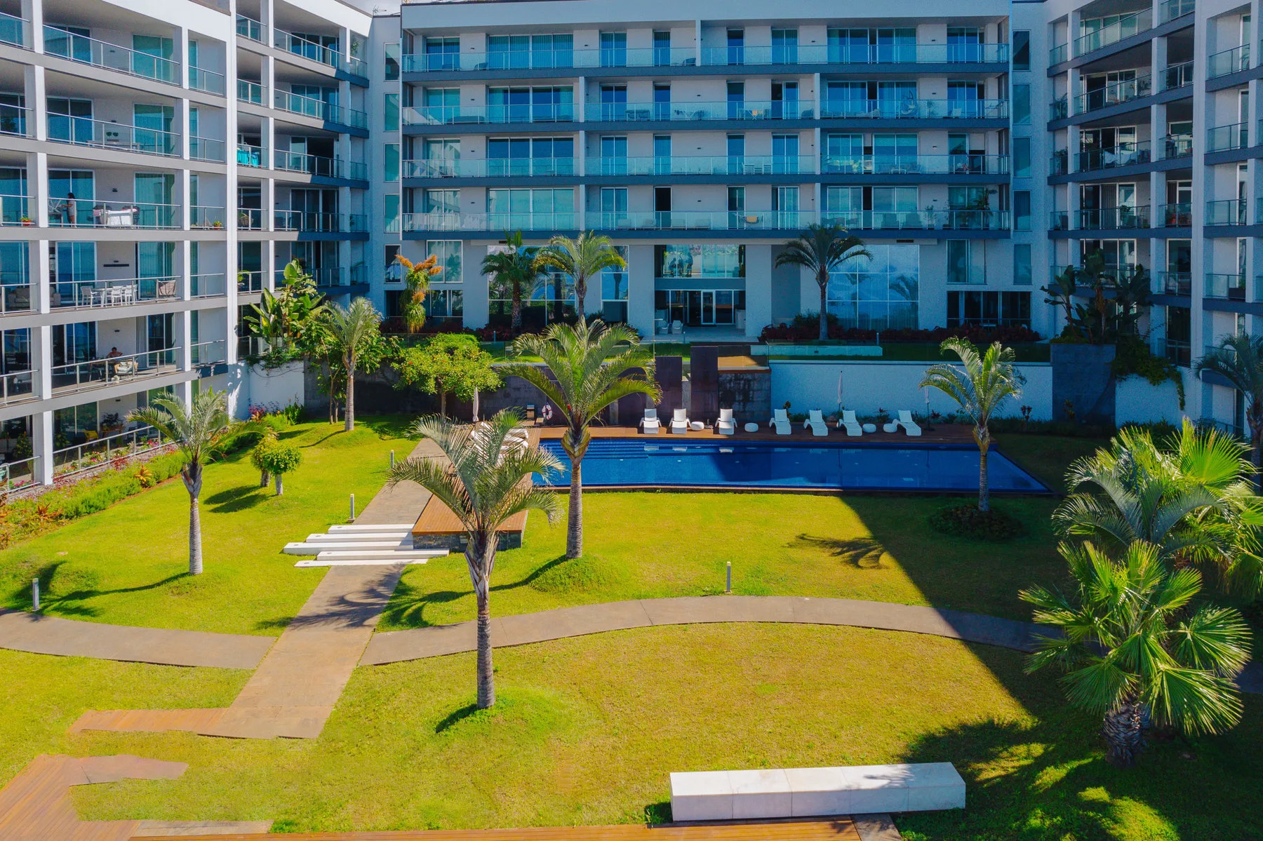 Apartment buildings surround a landscaped courtyard with a swimming pool.