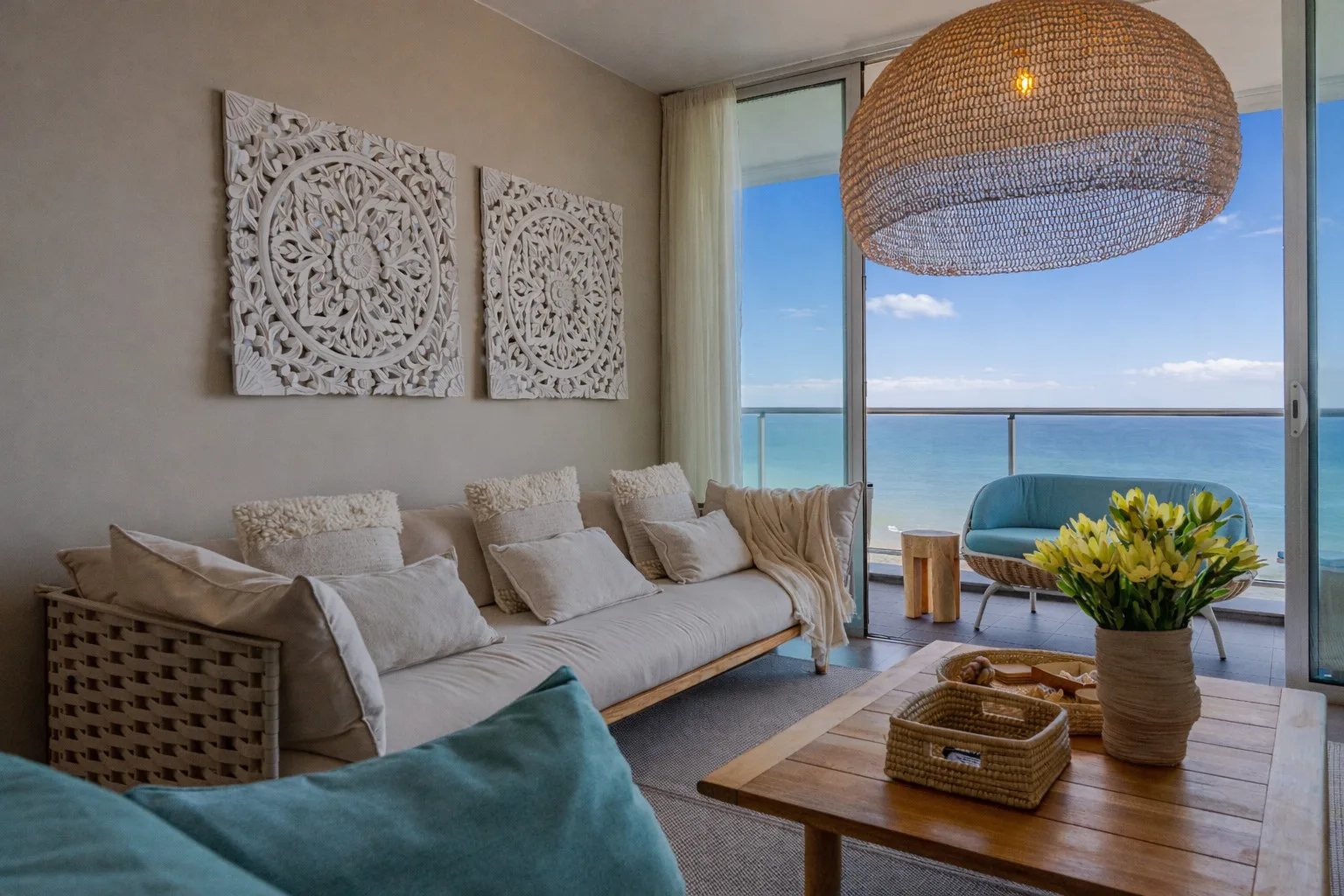 A bright living room with seating and a view of the ocean.