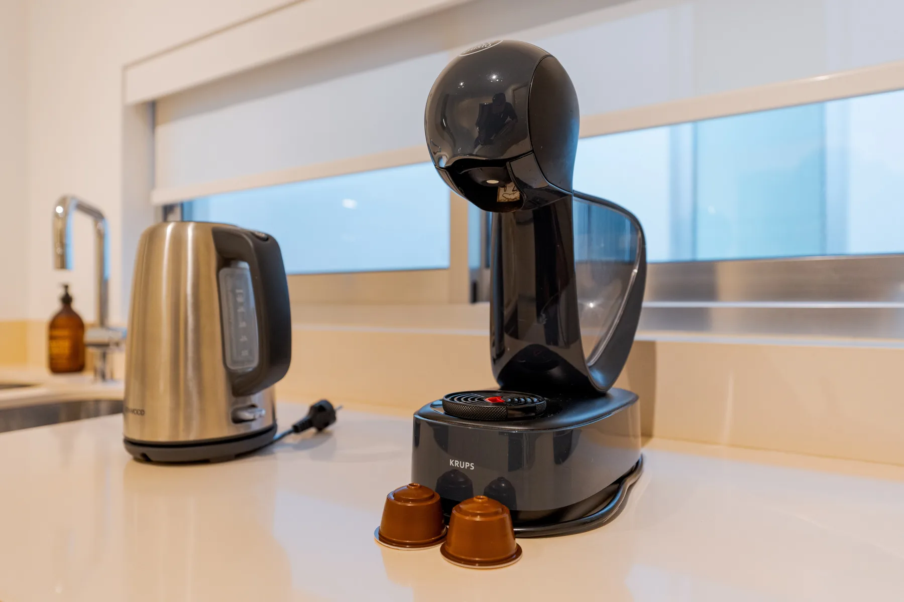 A kitchen counter with a coffee machine and electric kettle beneath a window.