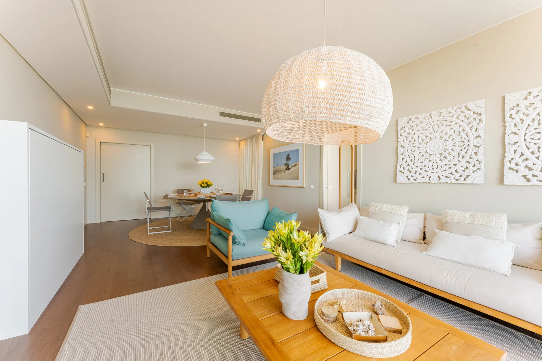 A bright living room with seating, a wooden coffee table, and dining area.
