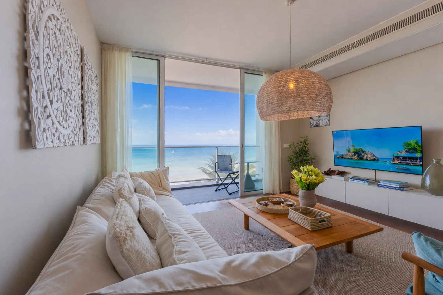 A living room opens onto a balcony overlooking the ocean.