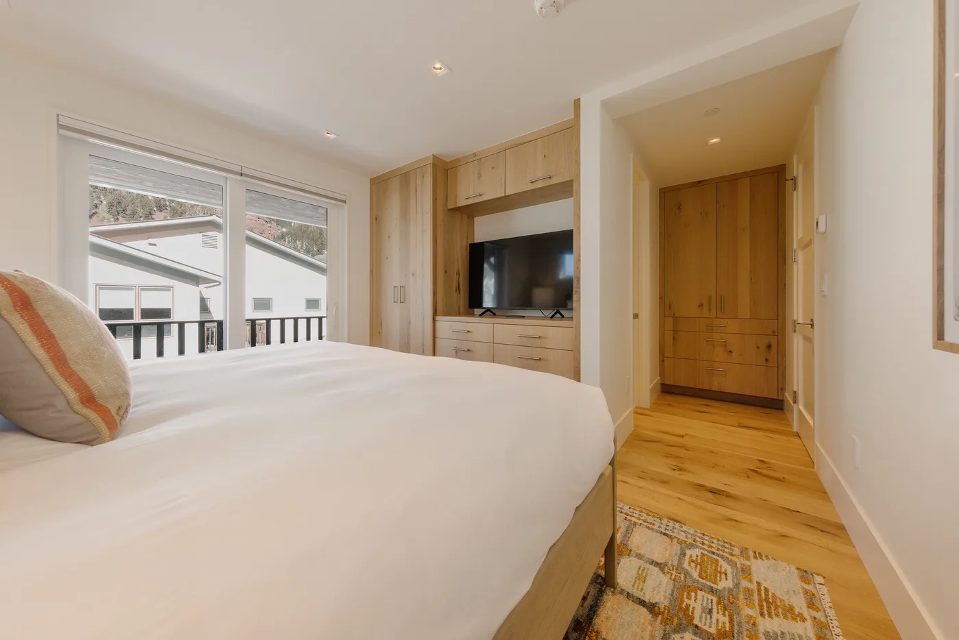 Un dormitorio con una cama, armarios de madera empotrados y un televisor.