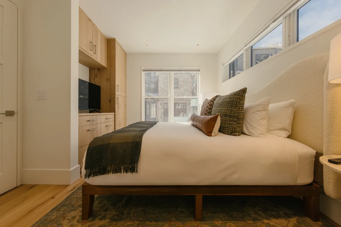 Un dormitorio luminoso con cama, almohadas y armarios empotrados.