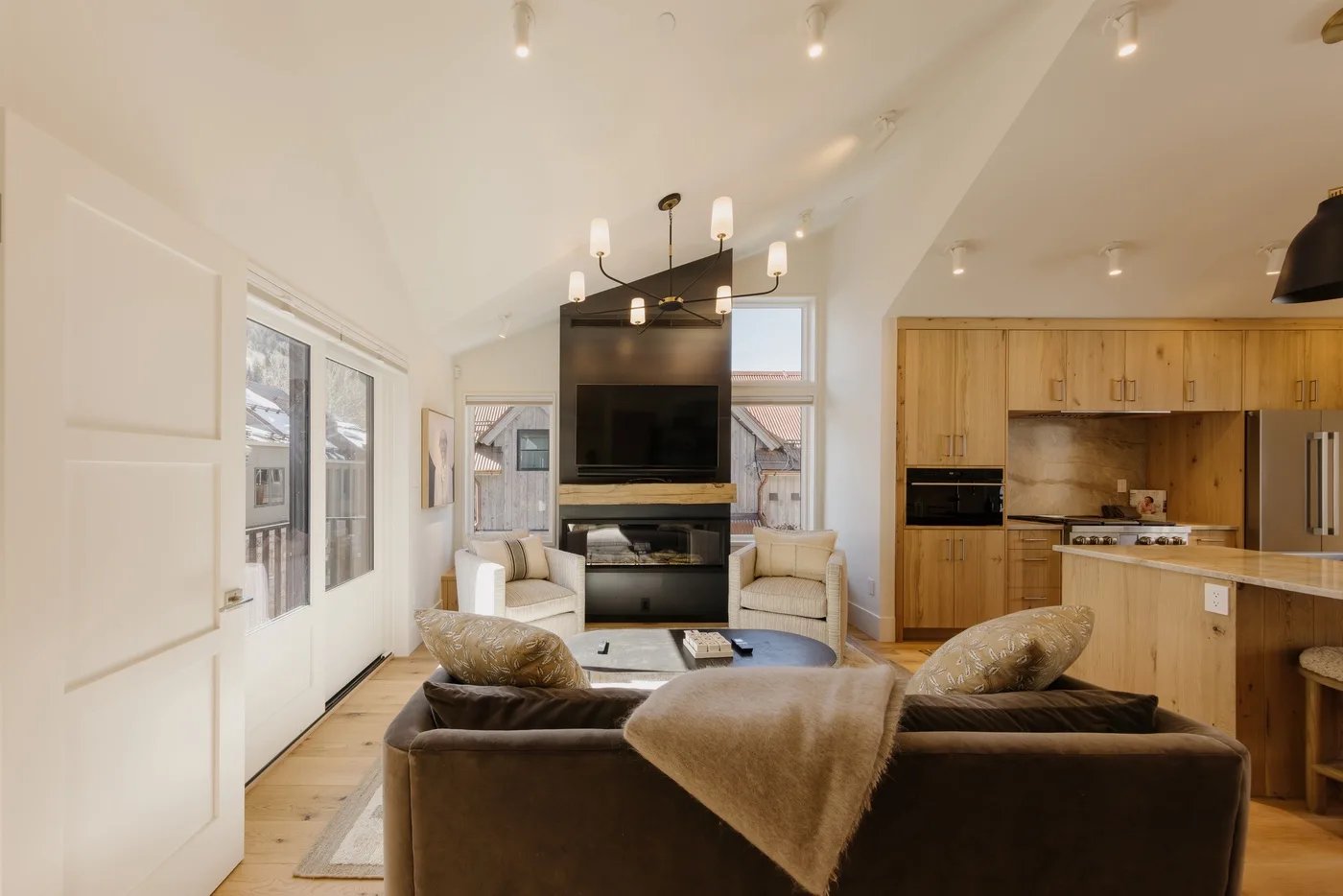 Sala de estar y cocina de espacio abierto con asientos alrededor de un televisor.