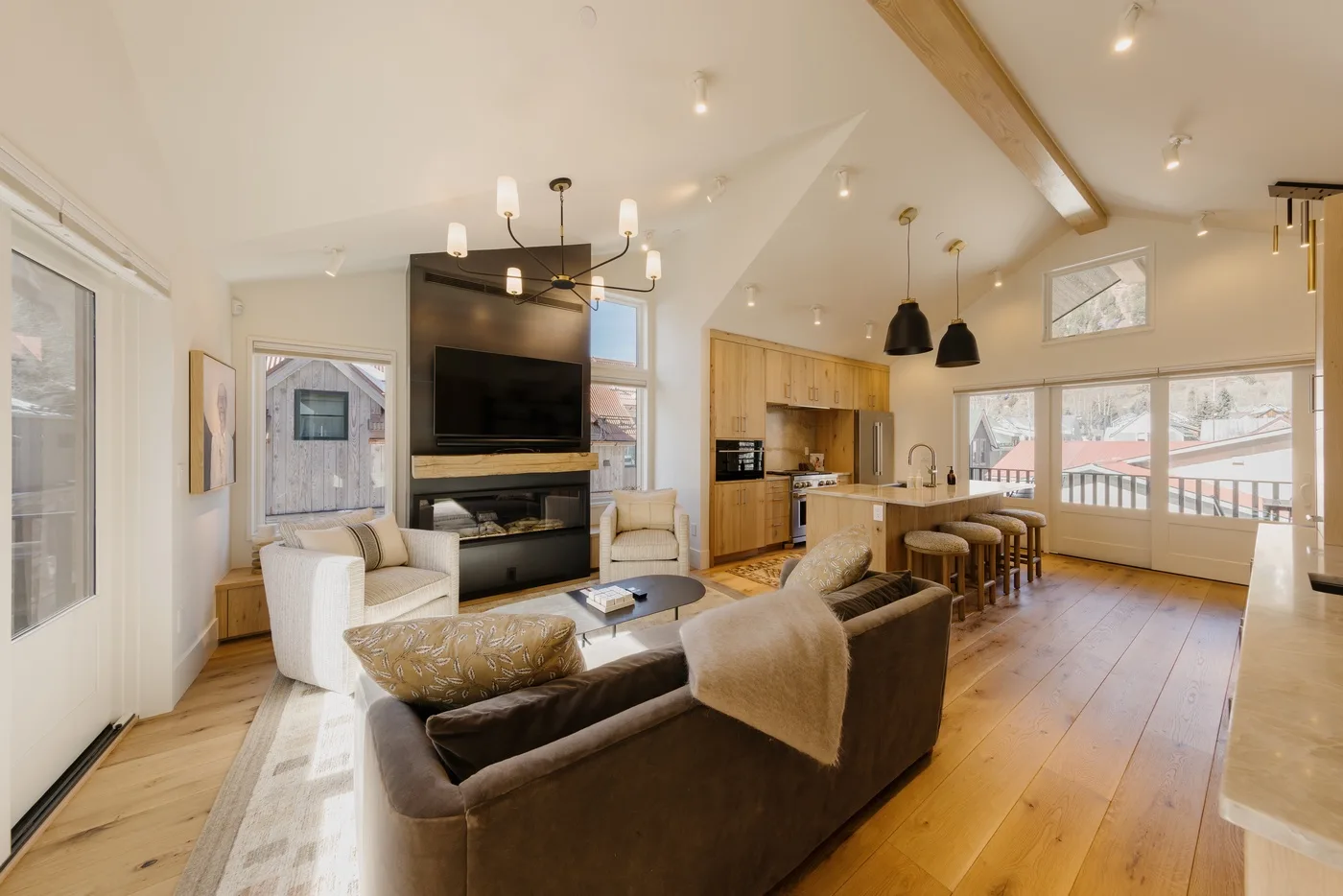 Sala de estar y cocina de planta abierta, con asientos junto a un televisor y una isla.