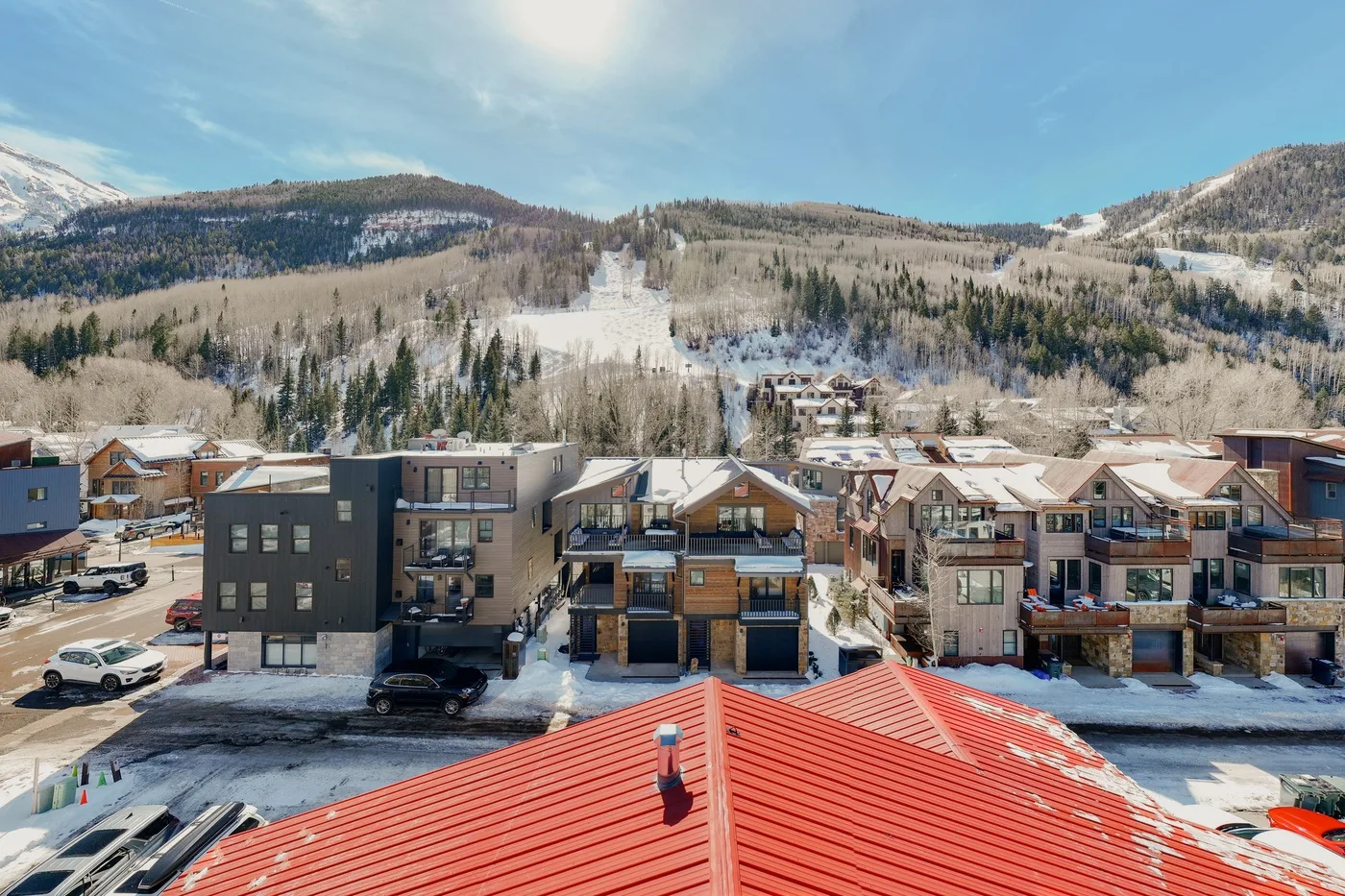 Edificios cubiertos de nieve se encuentran bajo un paisaje montañoso boscoso.