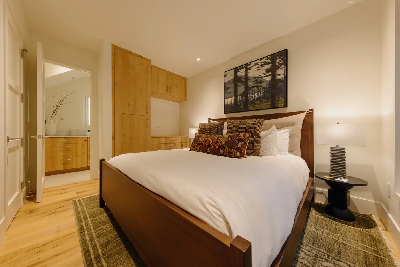 Un dormitorio con una cama grande, armarios de madera y un cuadro en la pared.