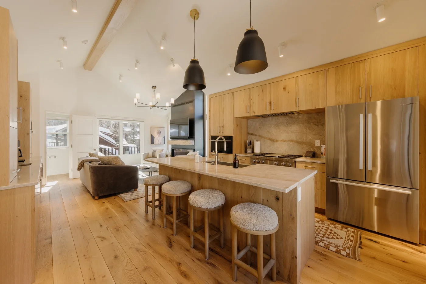 Una cocina abierta y sala de estar con una isla larga y lámparas colgantes.