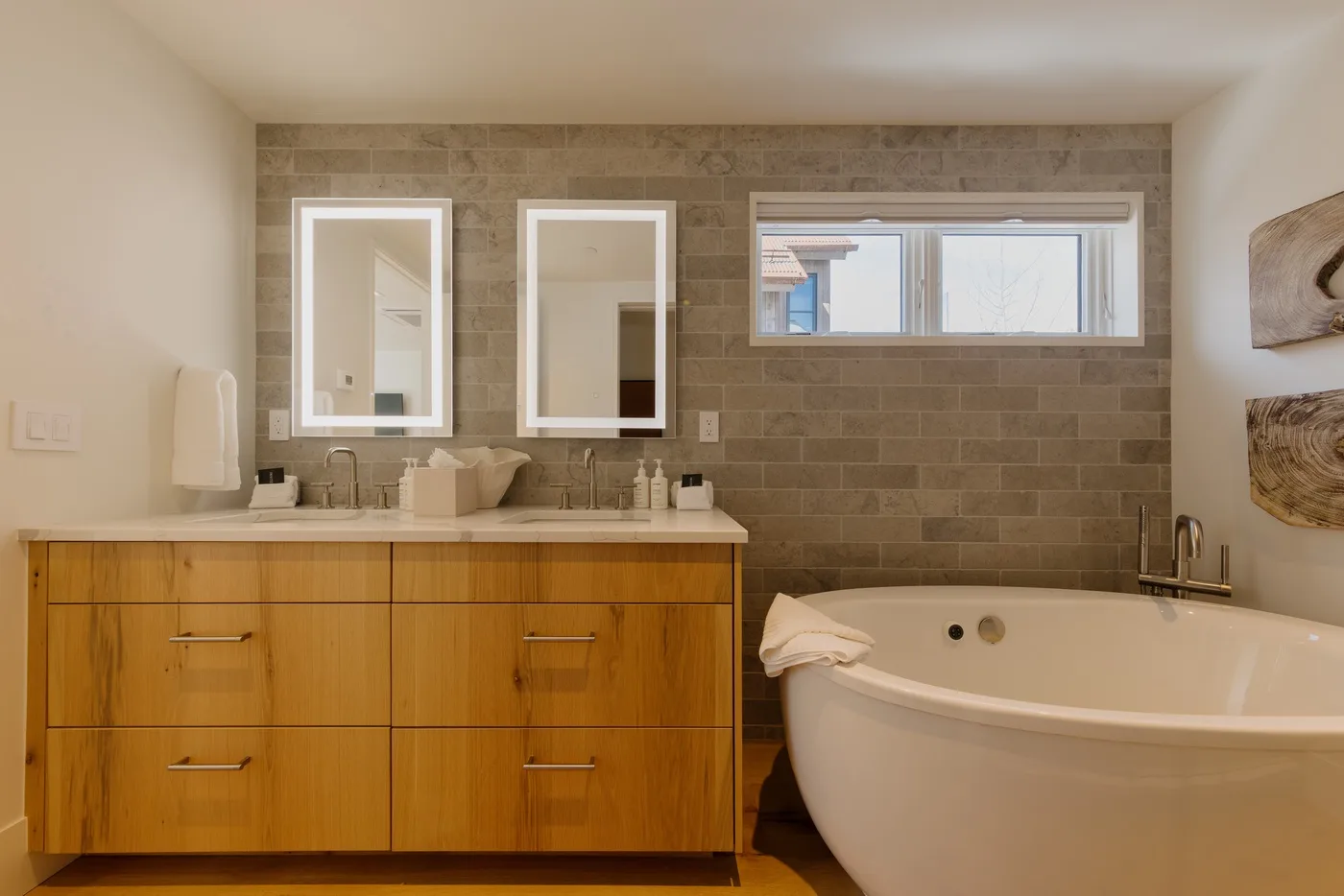 Un mueble de baño con dos espejos está junto a una bañera exenta.