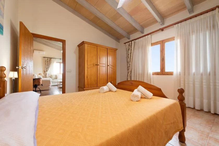 Un dormitorio con una cama grande, un armario de madera y una ventana con cortinas.
