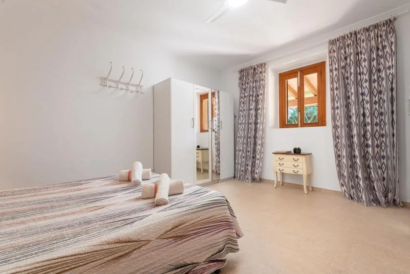 Un dormitorio luminoso con una cama hecha y cortinas estampadas.