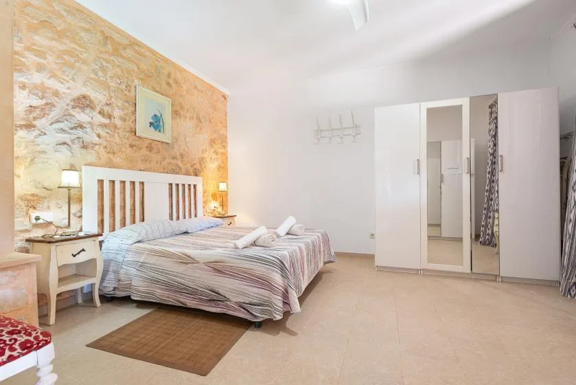 Un dormitorio luminoso con una cama, mesitas de noche y un armario con espejo.