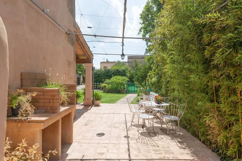 Un patio al aire libre con mesas y sillas junto a un jardín.