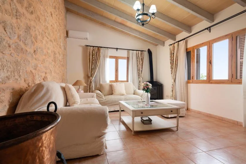 Una sala de estar luminosa con asientos, una mesa de centro y ventanas grandes.