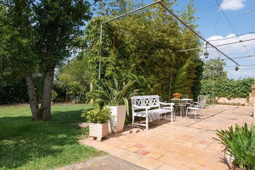 Un patio al aire libre con asientos blancos y un jardín.