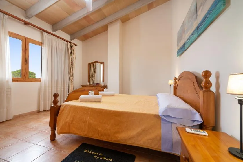 Un dormitorio con una cama de madera, ropa de cama clara y una ventana con cortinas.