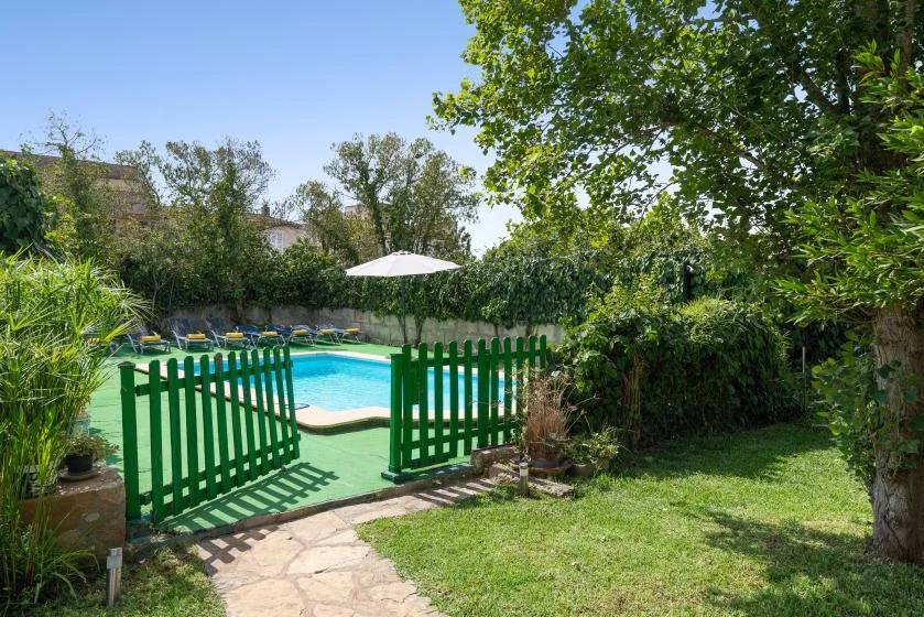 Un sendero del jardín pasa por una puerta verde hasta una piscina al aire libre.
