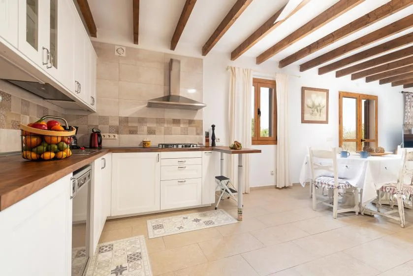 Una cocina luminosa se abre a un comedor con mesa y sillas.