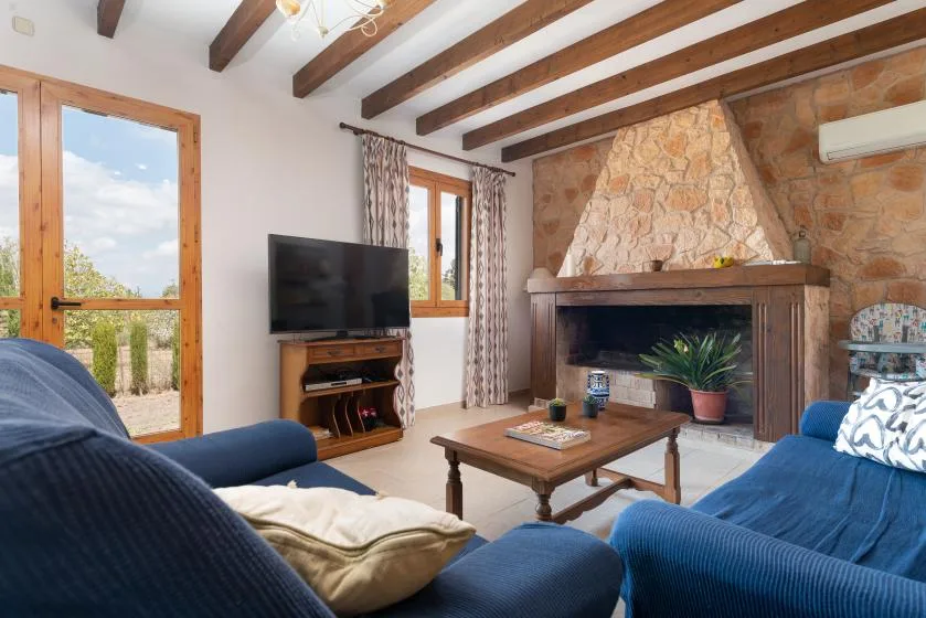 Una sala de estar con asientos azules, un televisor y una chimenea de piedra.