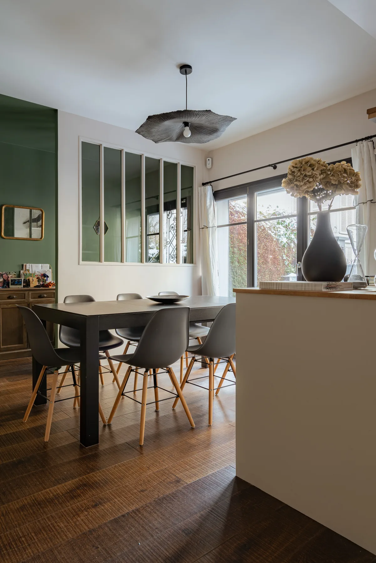 A dining area with a long table and chairs beside large windows.