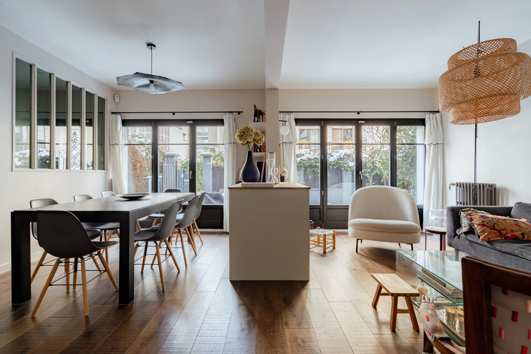 A bright open-plan living and dining room with large windows and seating.