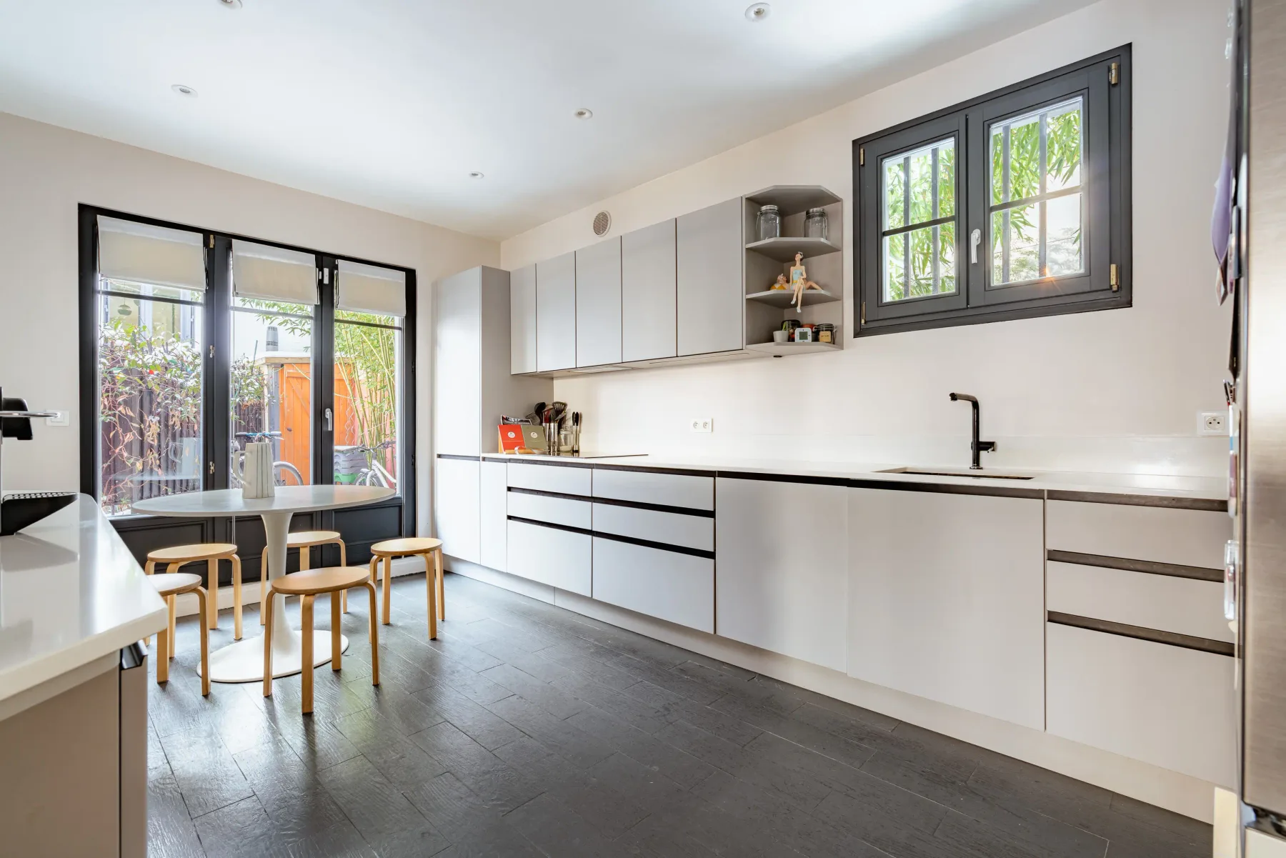 A bright kitchen with a dining table and large windows.