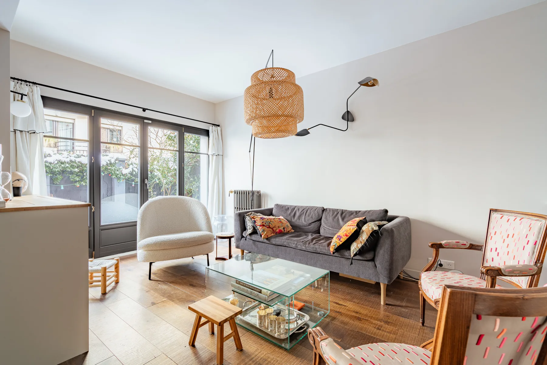 A bright living room with seating around a glass coffee table and large windows.