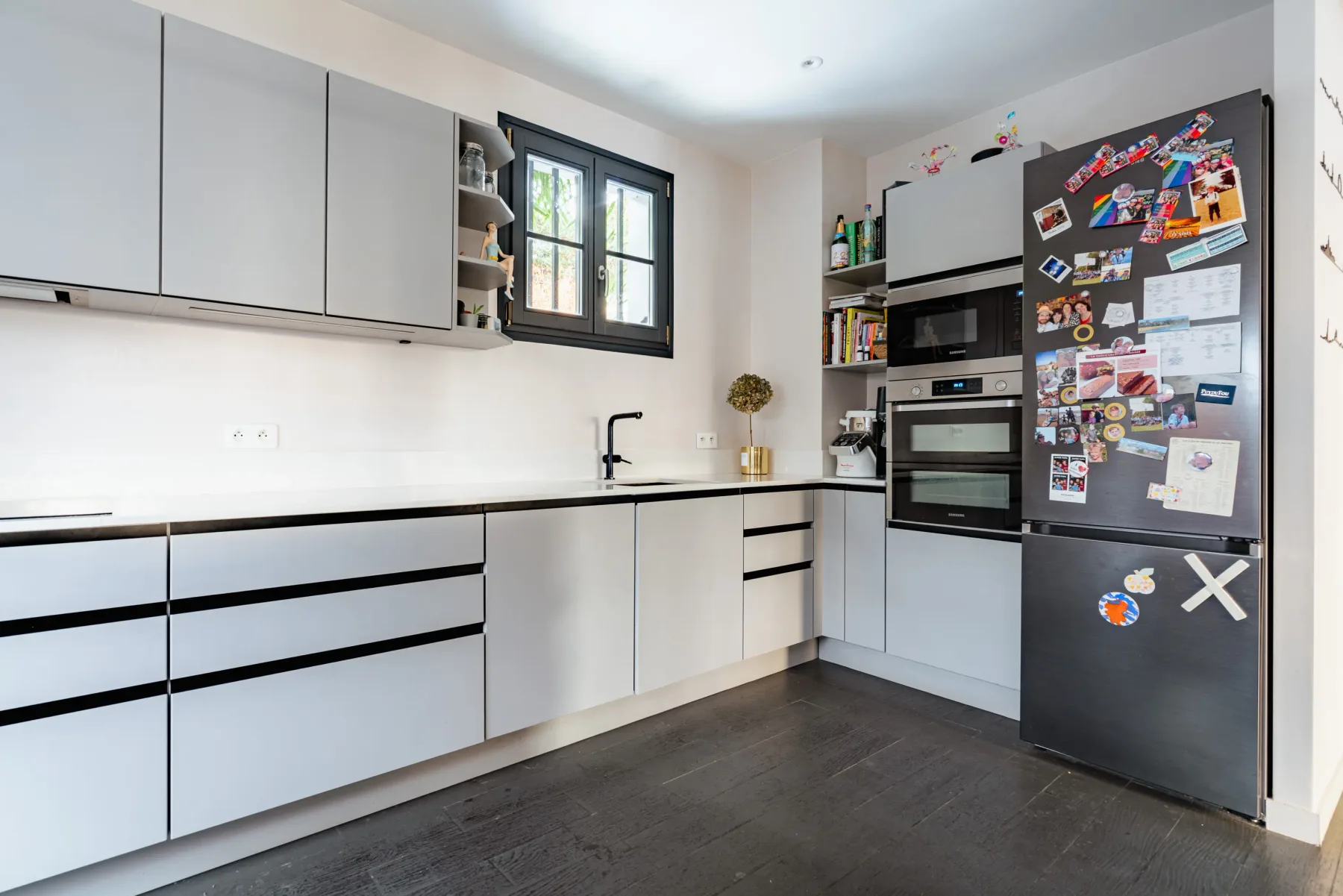 A bright kitchen with white cabinets, a sink, and a refrigerator.
