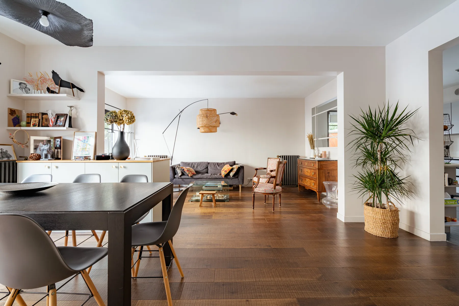 An open-plan living and dining area with a table, seating, and a potted plant.