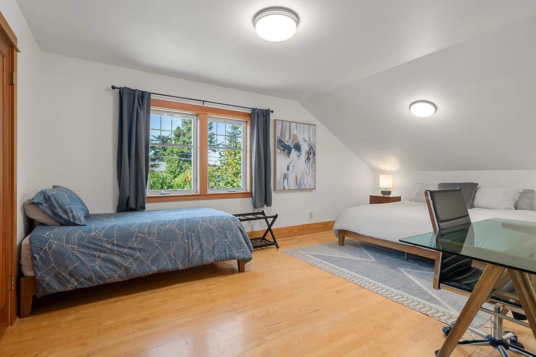 Un dormitorio con dos camas, una ventana y una mesa de vidrio.