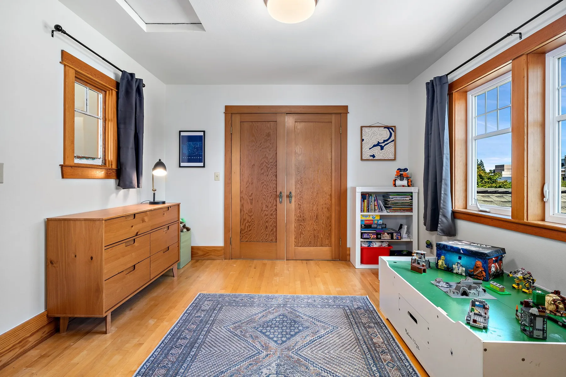 Una habitación luminosa con suelo de madera, ventanas grandes y una mesa de juegos.