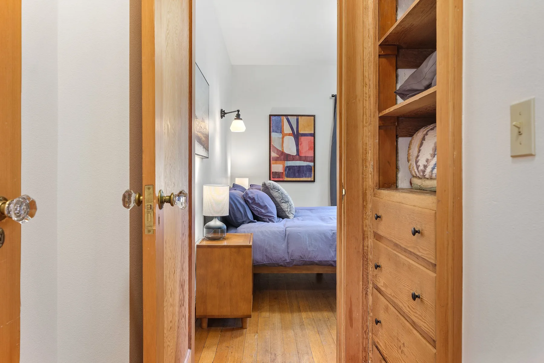 Un dormitorio con una cama, una mesita de noche y estanterías de madera.