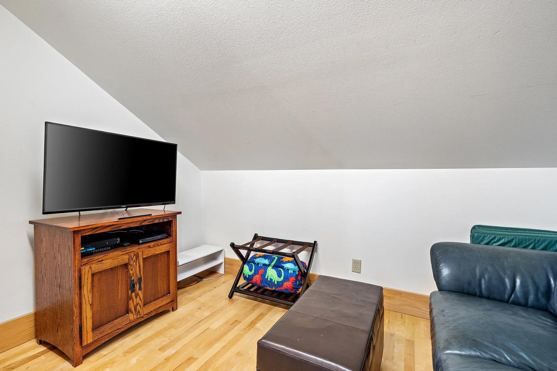 Una sala de estar con un televisor sobre un mueble de madera y asientos.