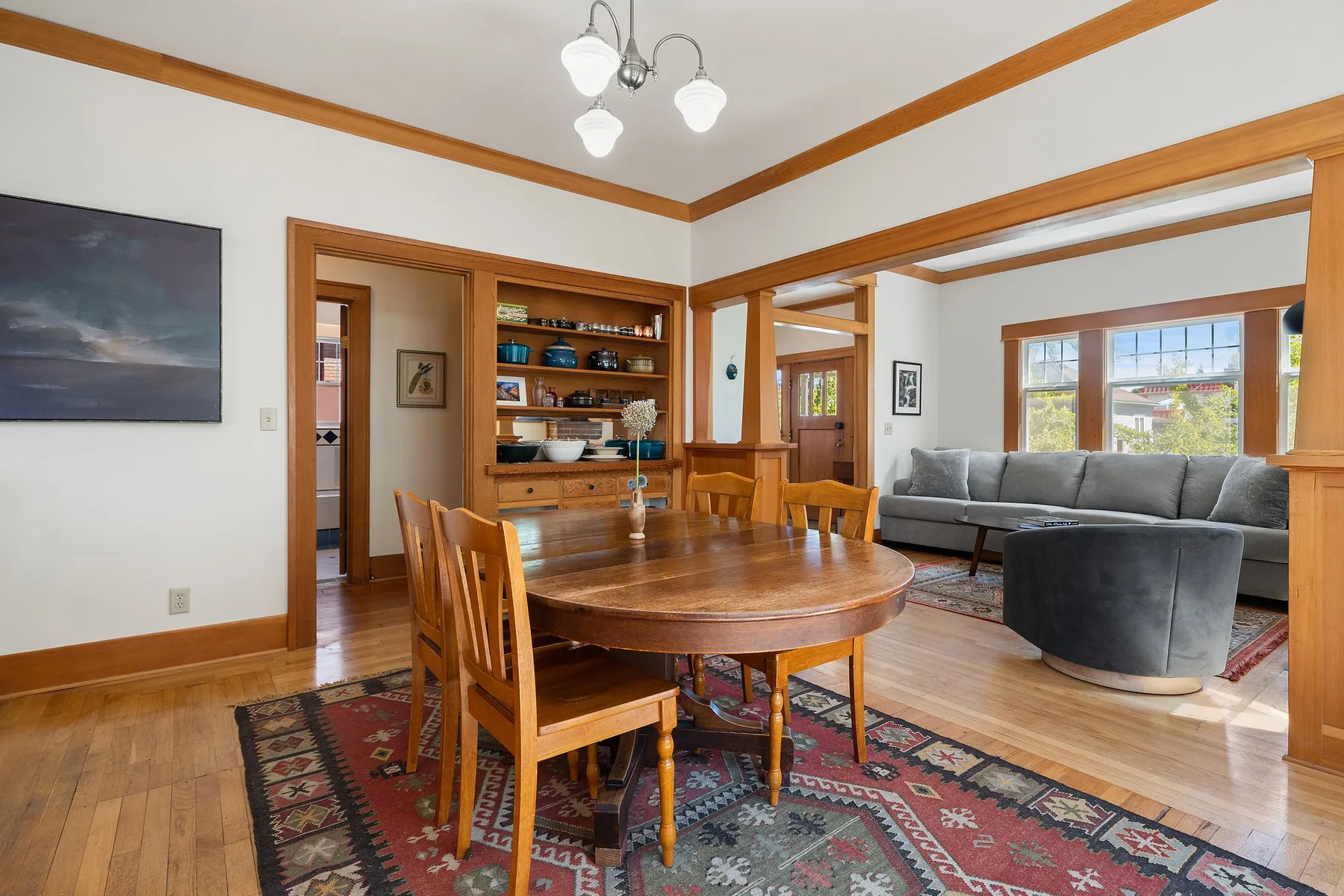Comedor con mesa de madera y asientos junto a una sala de estar.
