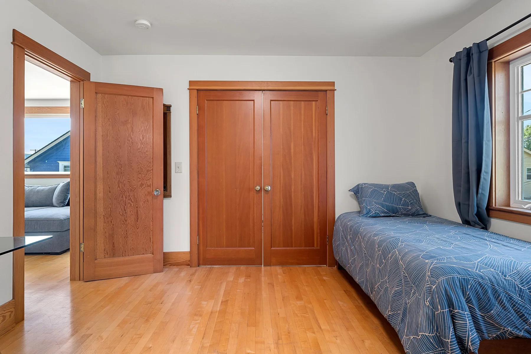 Un dormitorio con una cama junto a una ventana y puertas de madera.
