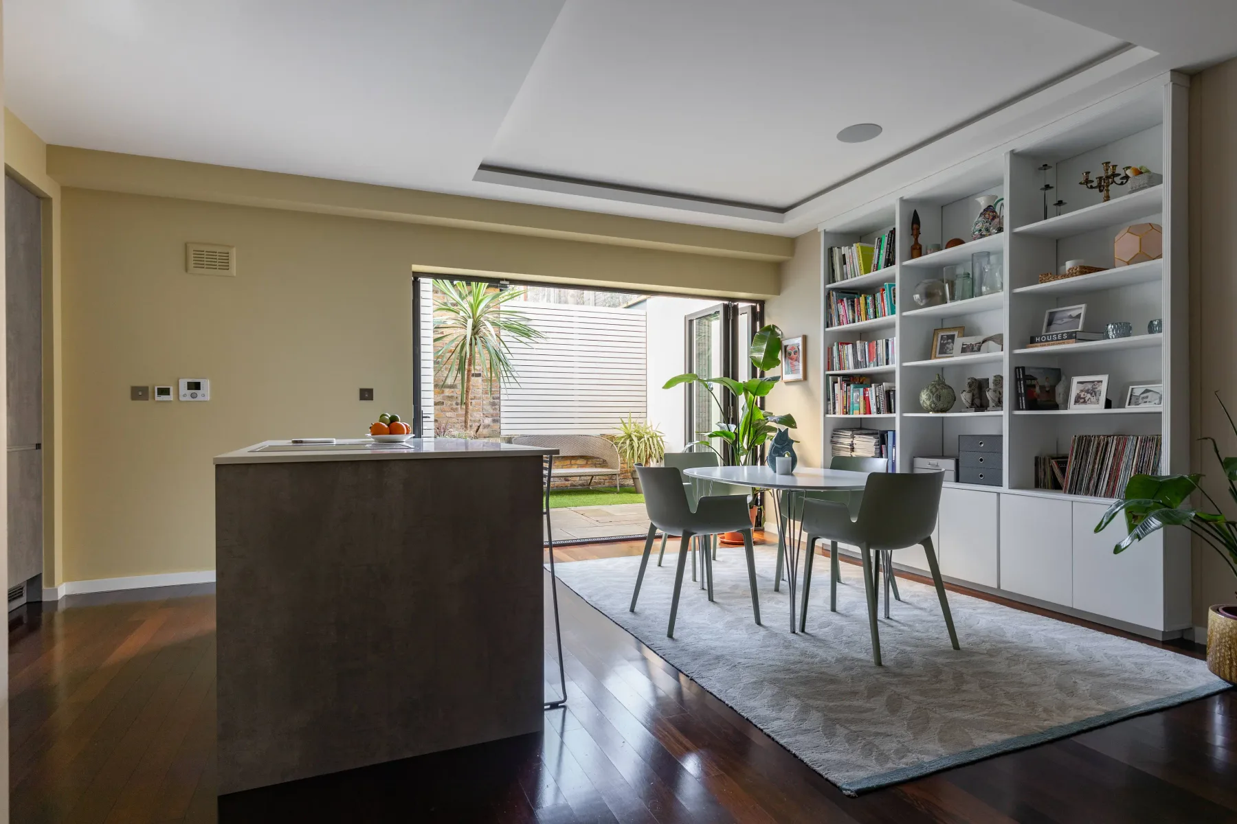 Una cocina abierta al comedor, con estanterías empotradas y una ventana amplia.