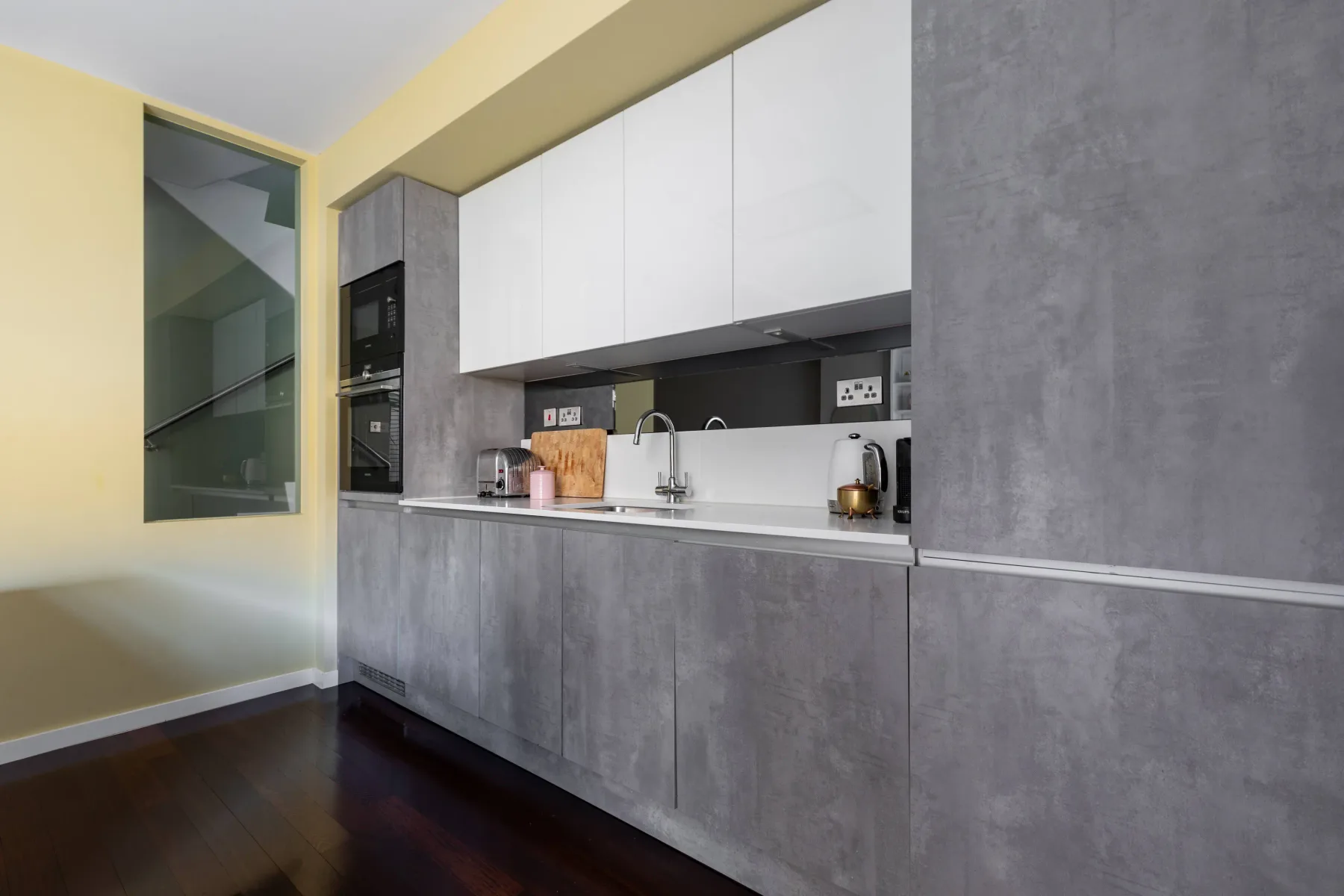Una cocina moderna con armarios grises, gabinetes blancos superiores y una encimera.