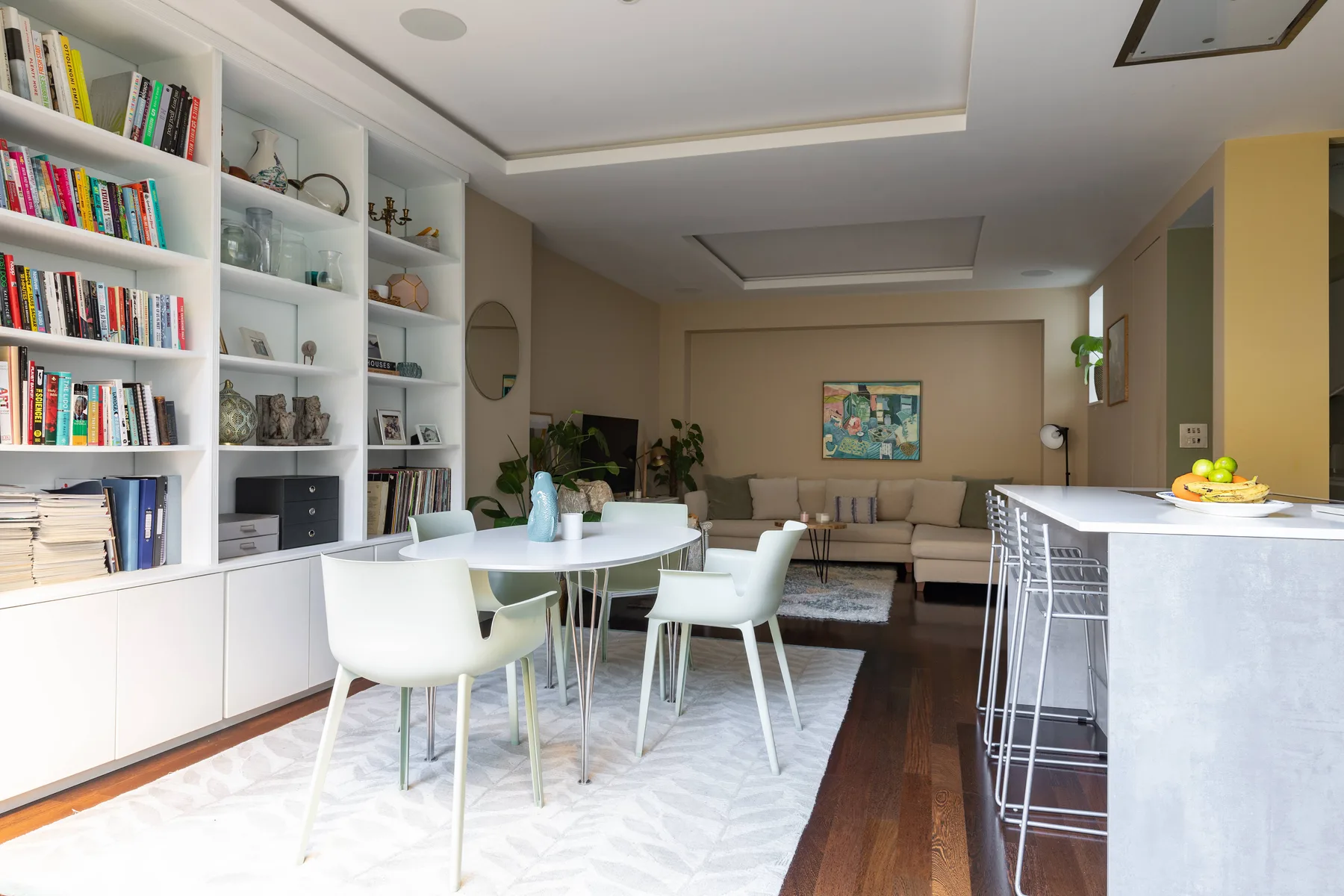 Una luminosa sala-comedor diáfana con mesa, asientos y estanterías empotradas.