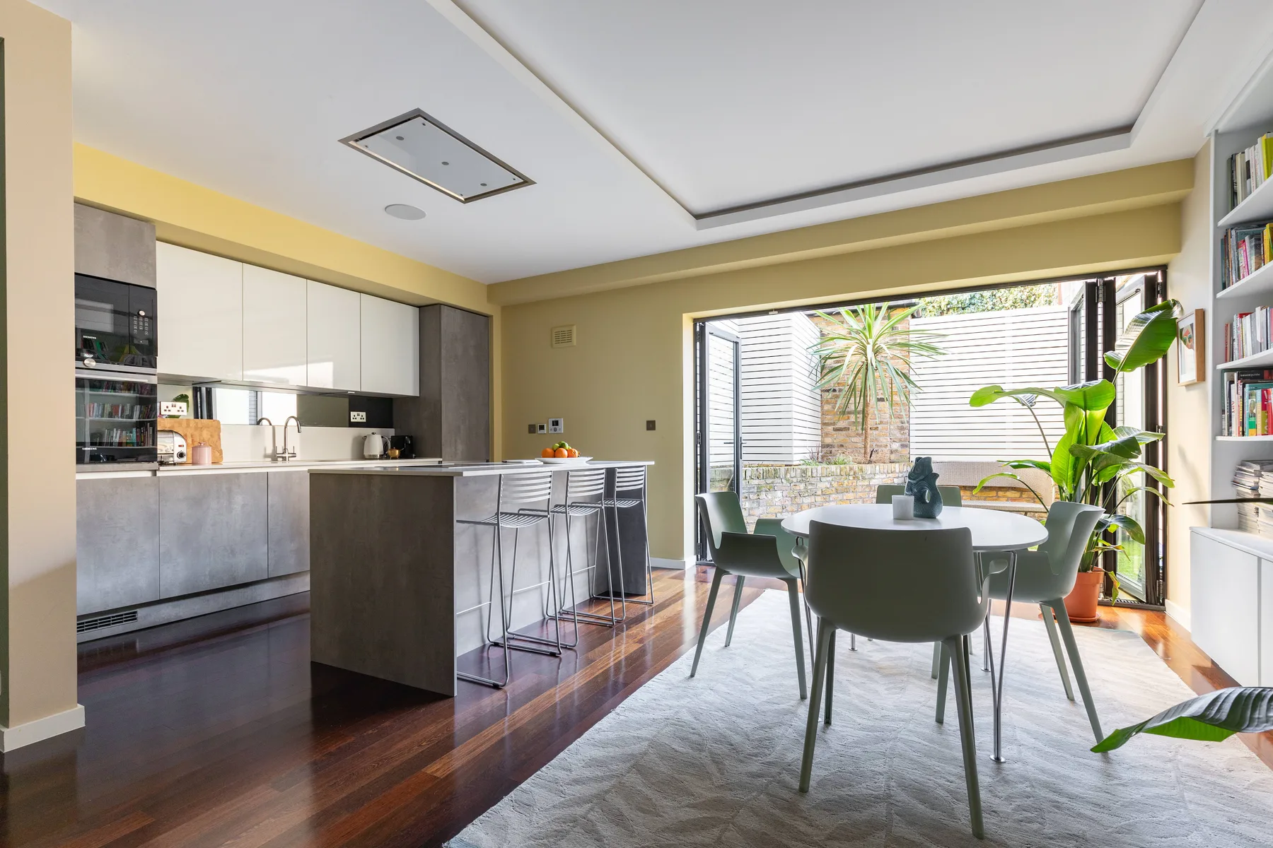 Una cocina abierta con comedor y una mesa junto a grandes ventanales.