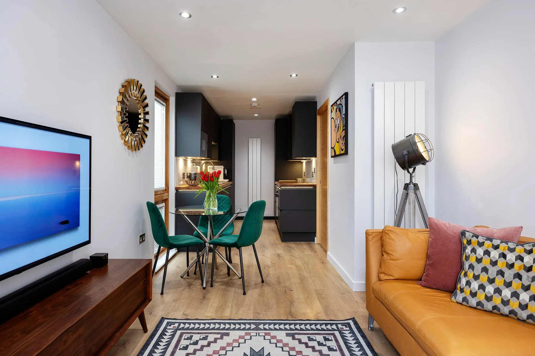 A modern living and dining area with a table, seating, and television.